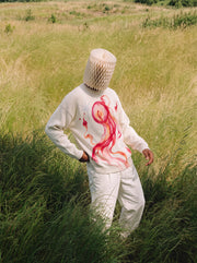 Model wearing Hitodama Knit (Akane), front view in a grassy field